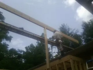 Carpenter setting a ridge beam over a new addition frame — Ice Dam Removal by Roofing Brothers in Rubicon