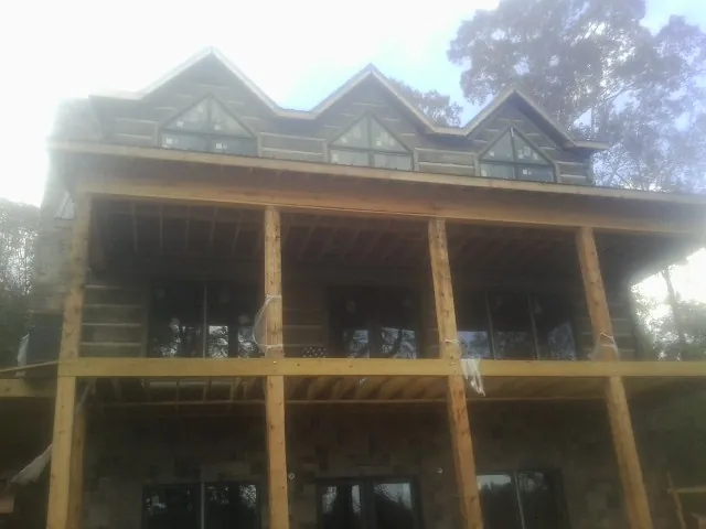 Dormers and porch framing on a large log home under construction — Roof Coating work by our crew in Rubicon