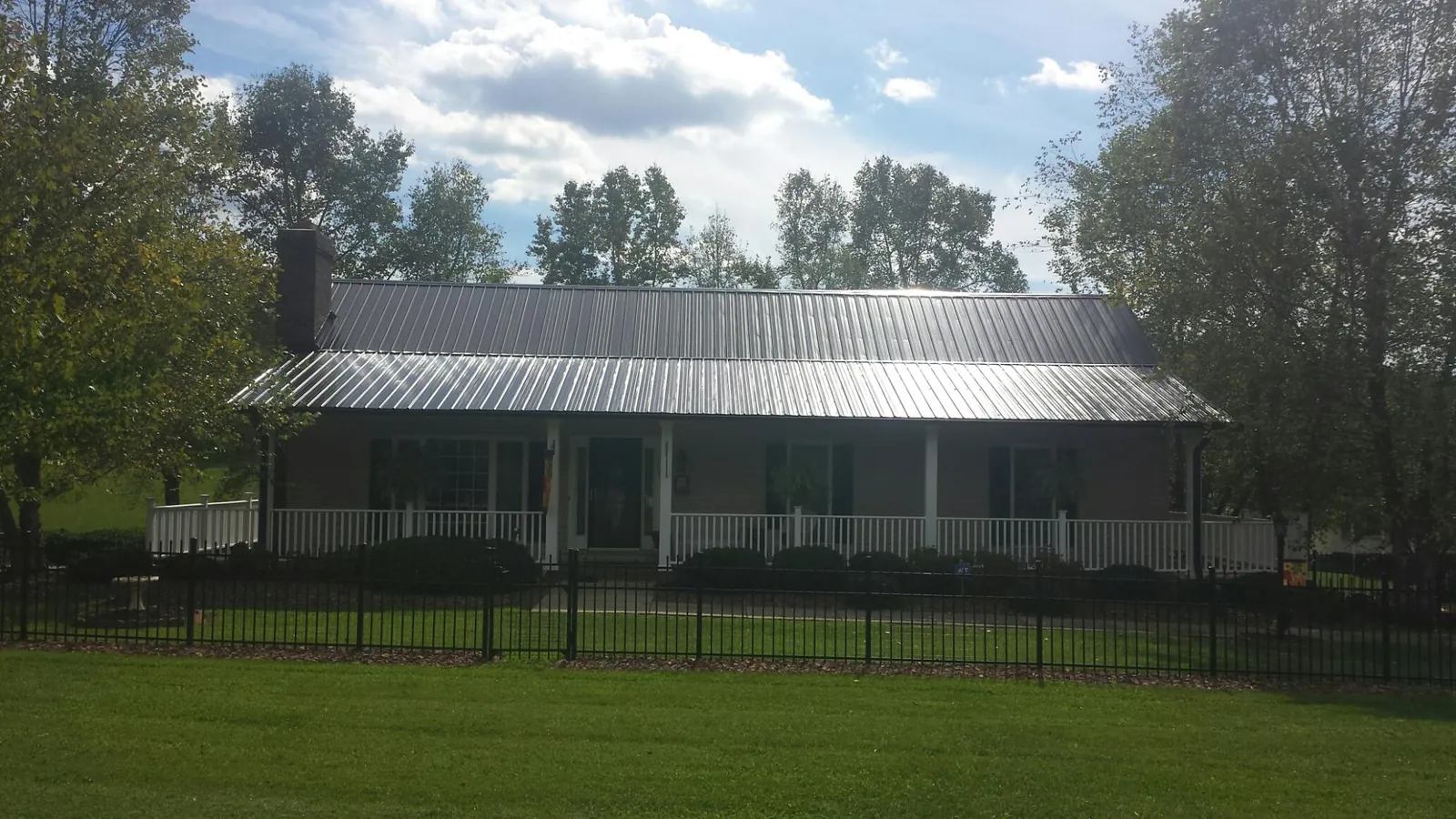 Gray metal roof on a brick ranch with a full width front porch — Gutter Guard Installation work by our crew in Rubicon